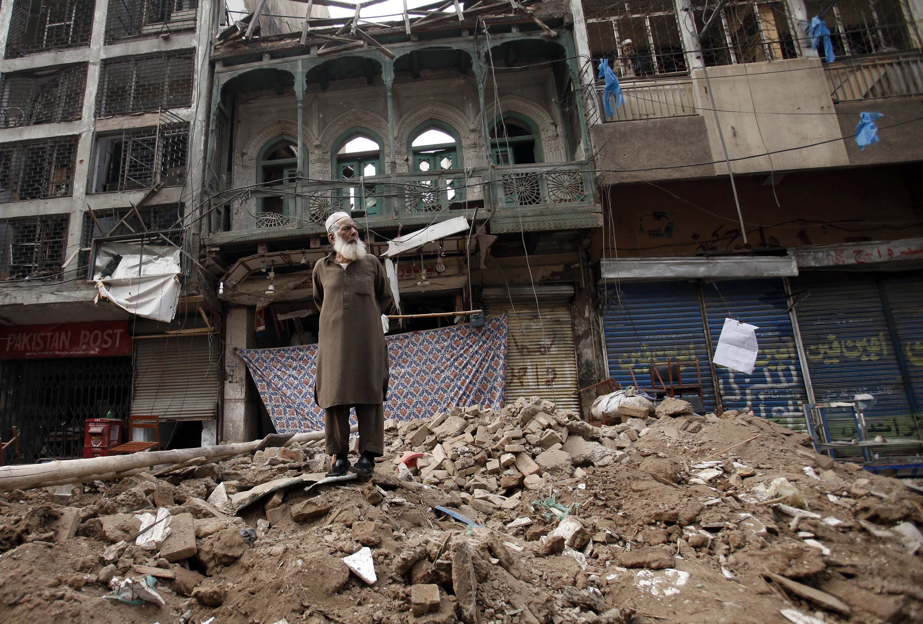 A man stands on a pile of rubble in front of a damaged building after it was hit by a bomb blast. Photo: Reuters