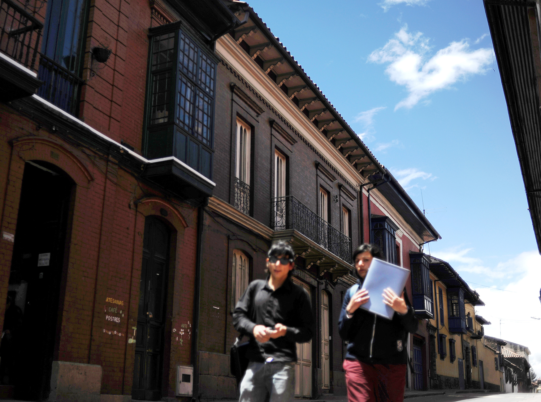 Two young women walk down a street in the historic neighborhood of La Candelaria in Bogota. Photo: AP