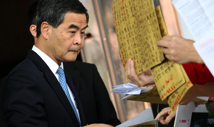 Chief Executive Leung Chun-ying receives petitions outside government headquarters in Admiralty before an Executive Council meeting on Tuesday. Photo: Felix Wong