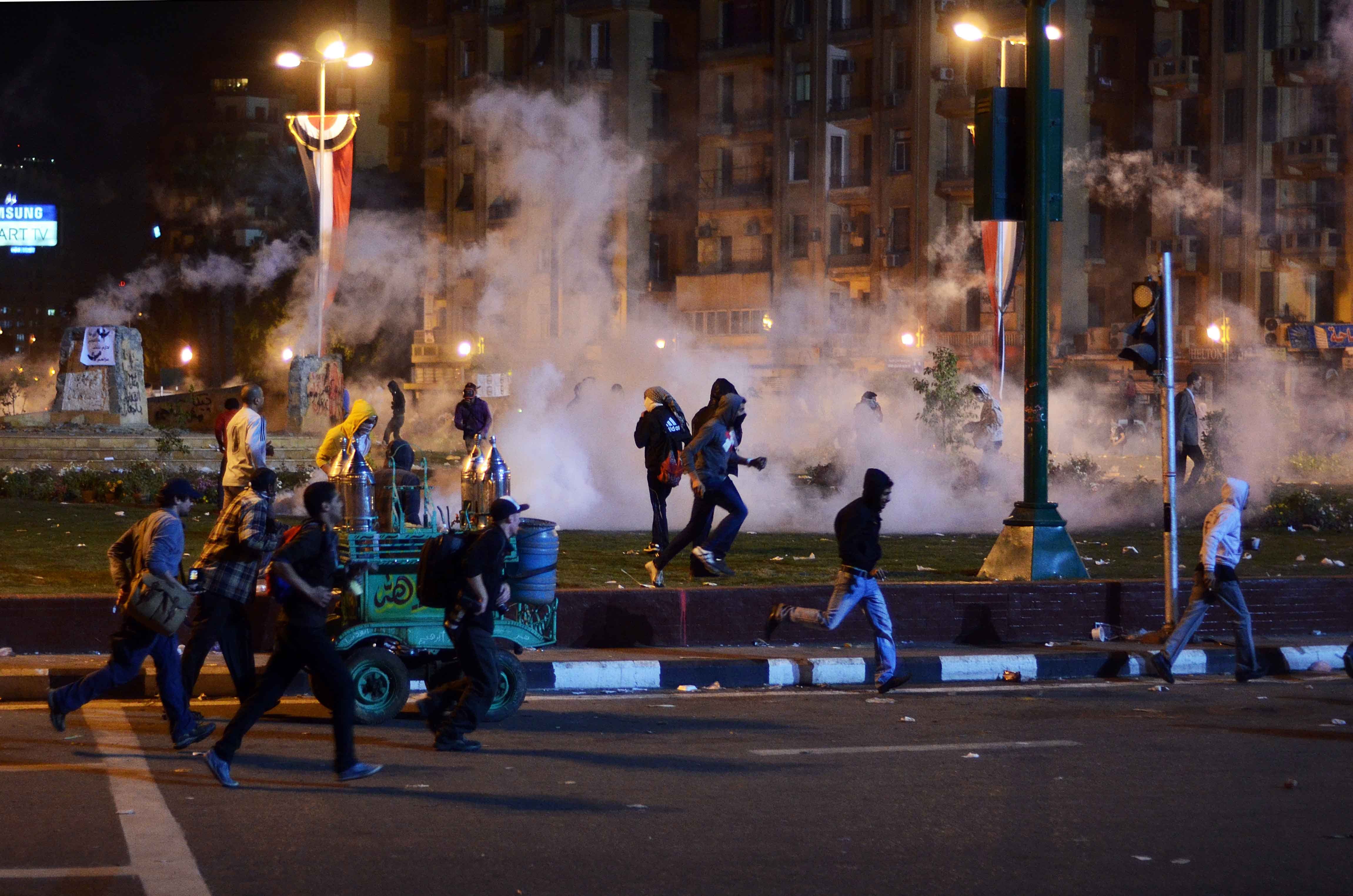Egyptian anti-military demonstrators run for cover from tear gas fired by riot police during clashes in Tahrir Square. Photo: AFP