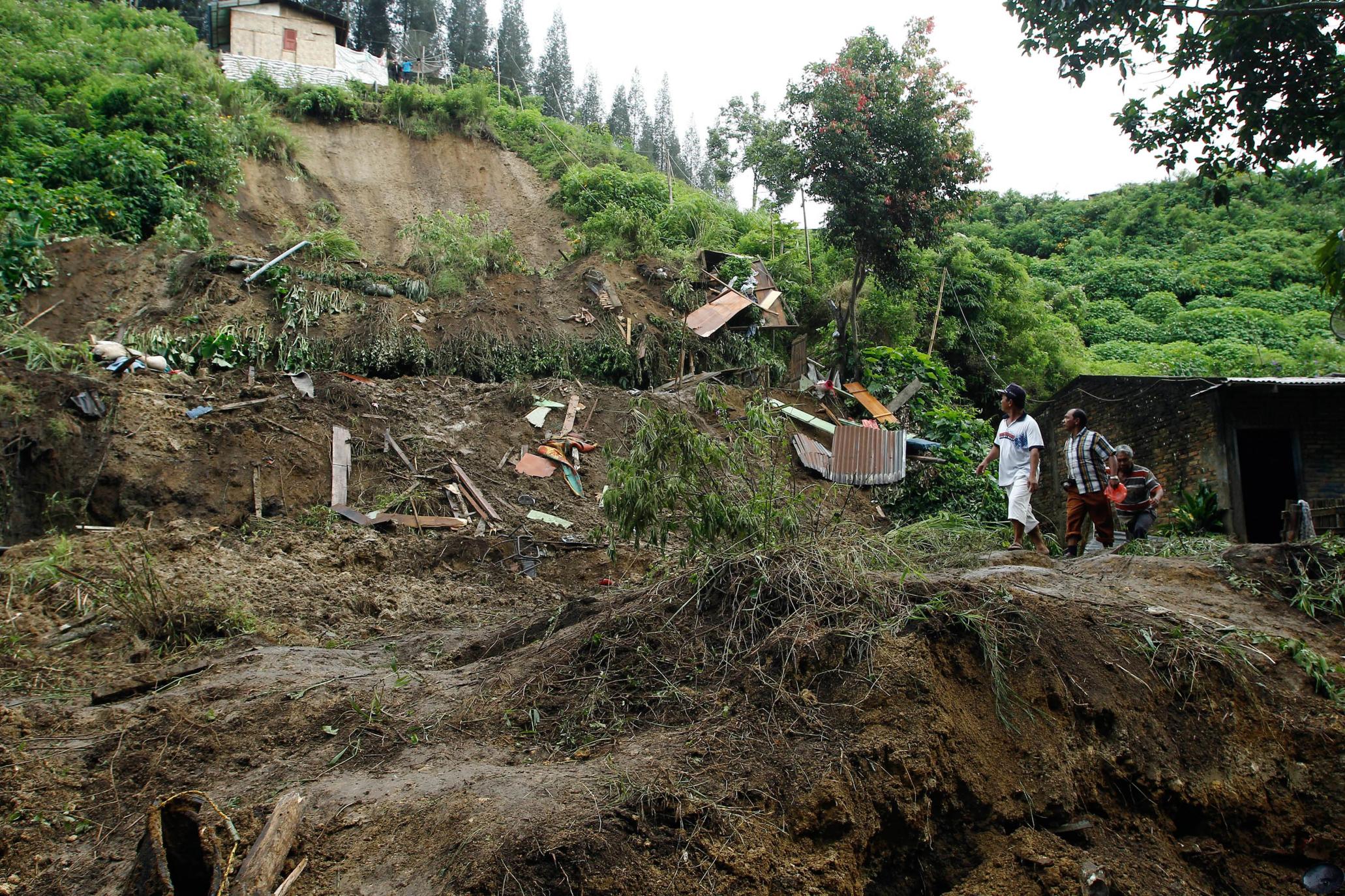 Indonesian villagers walk in the area after heavy rain swept and killed nine people. Photo: AFP