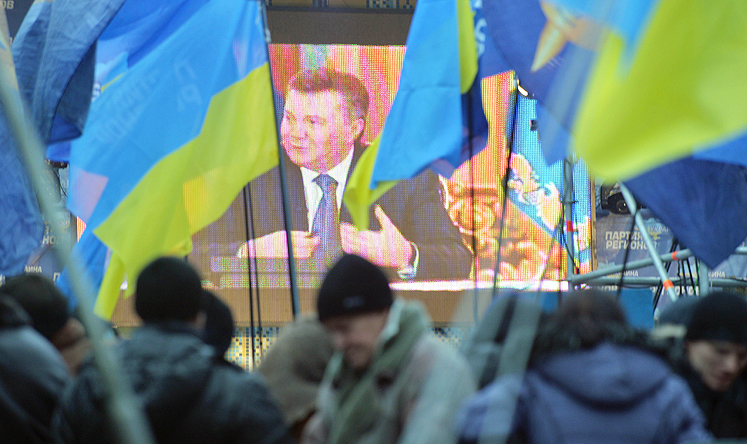 Supporters of Ukrainian President Viktor Yanukovych stand outside the parliament building in Kiev on Thursday as they watch a press conference relayed on a giant screen. Photo: AFP