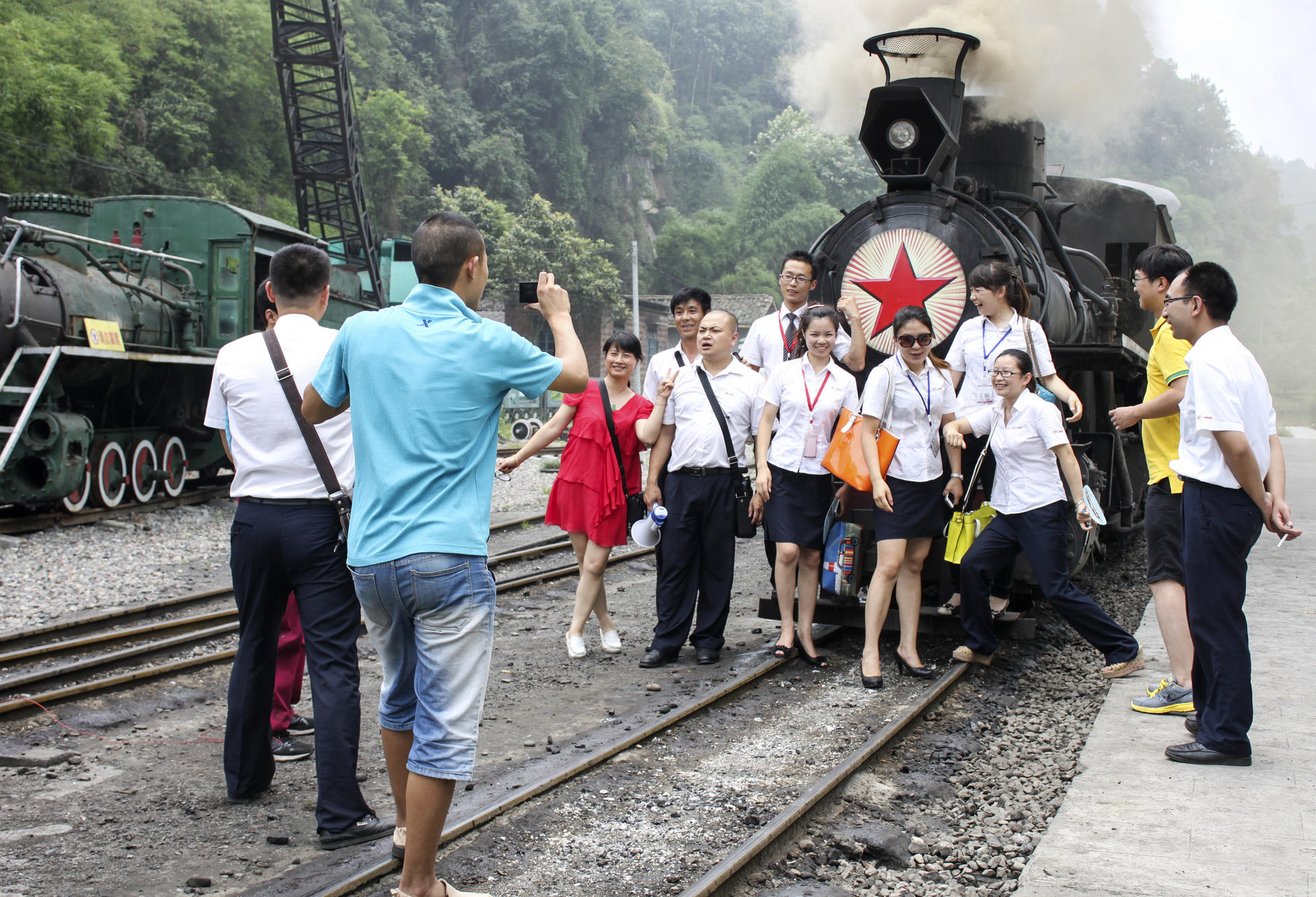 Visitors pose in front a steam engine on the Jiayang Railway line.