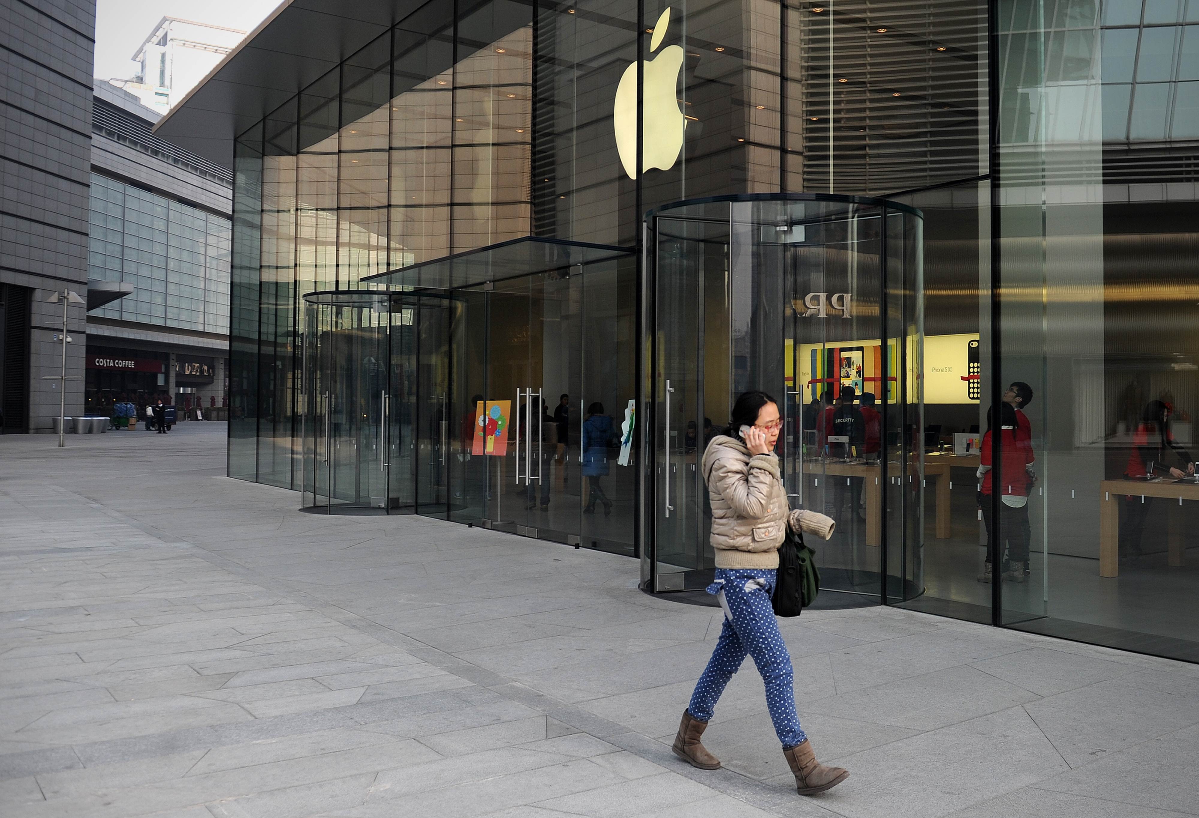 A woman uses a mobile phone as she walks past an Apple store in Beijing on January 17, 2014.Photo: AFP