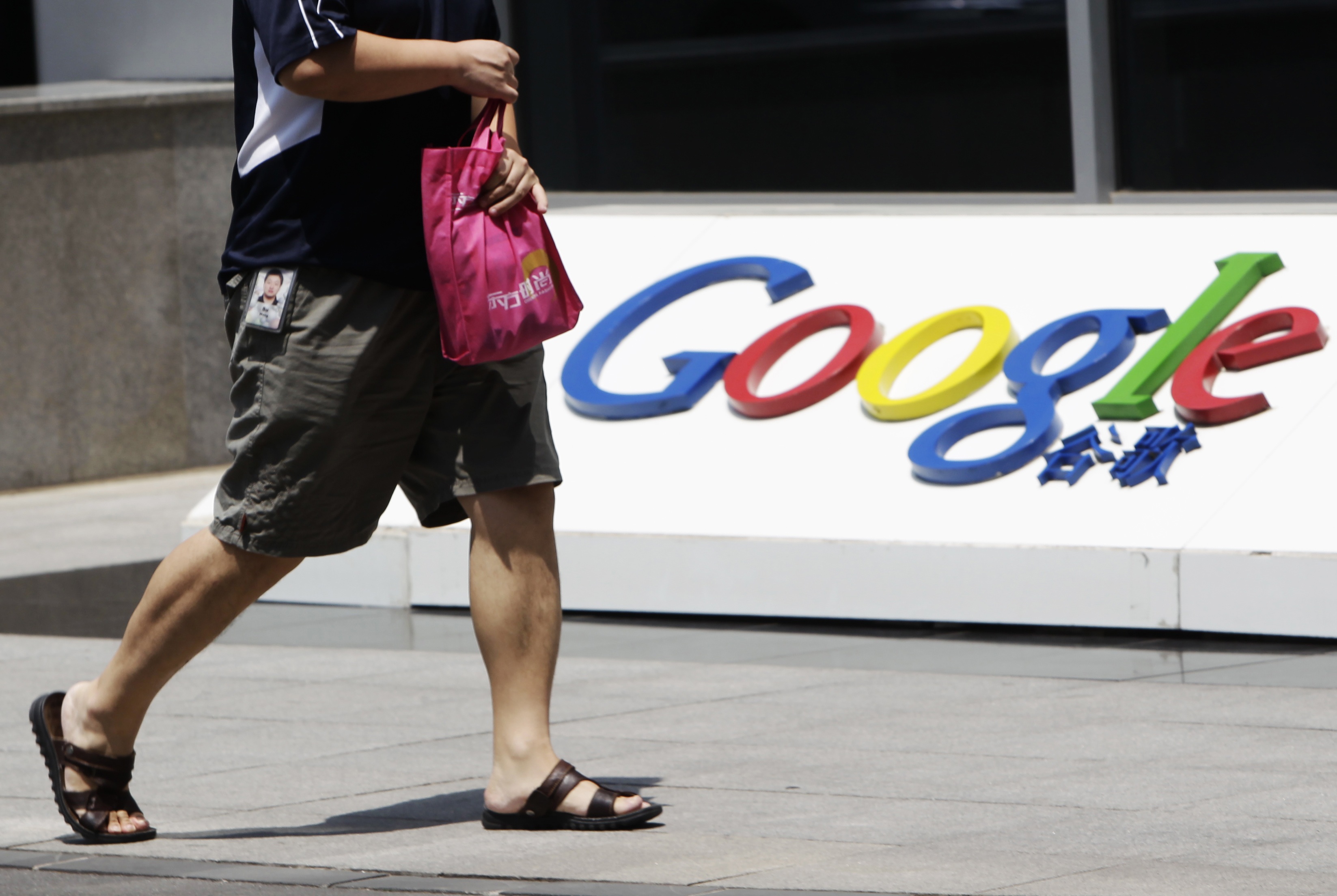 An employee walks past the logo of Google in front of its former headquarters, in Beijing June 2, 2011. Photo: Reuters