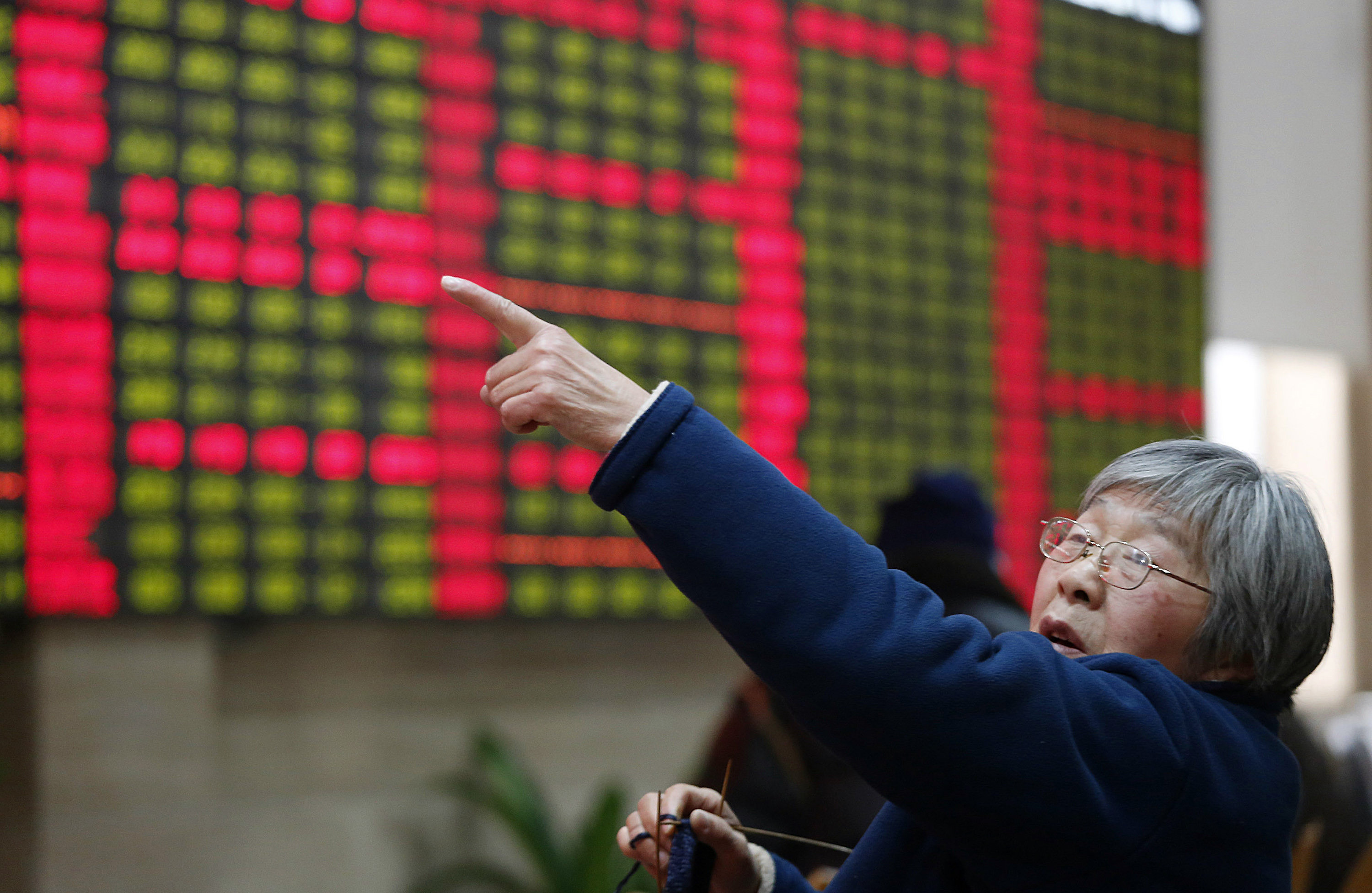 An investor gestures in front of the stock price monitor at a private securities company in Shanghai on December 26, 2013. Photo: AP