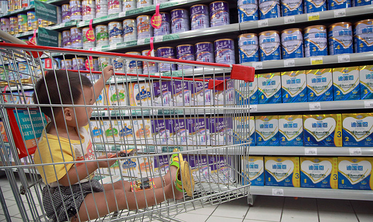 A baby watches as his mother selects milk powder in a supermarket in Haikou, Hainan province. Photo: AFP