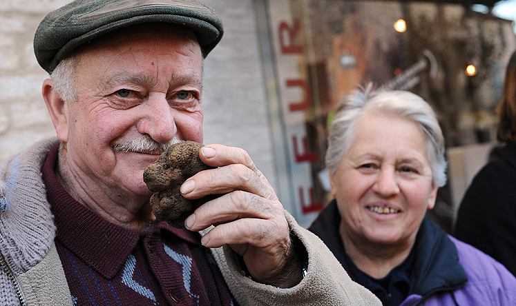 A trader sniffs a truffle in a market in southwest France. Photo: AFP