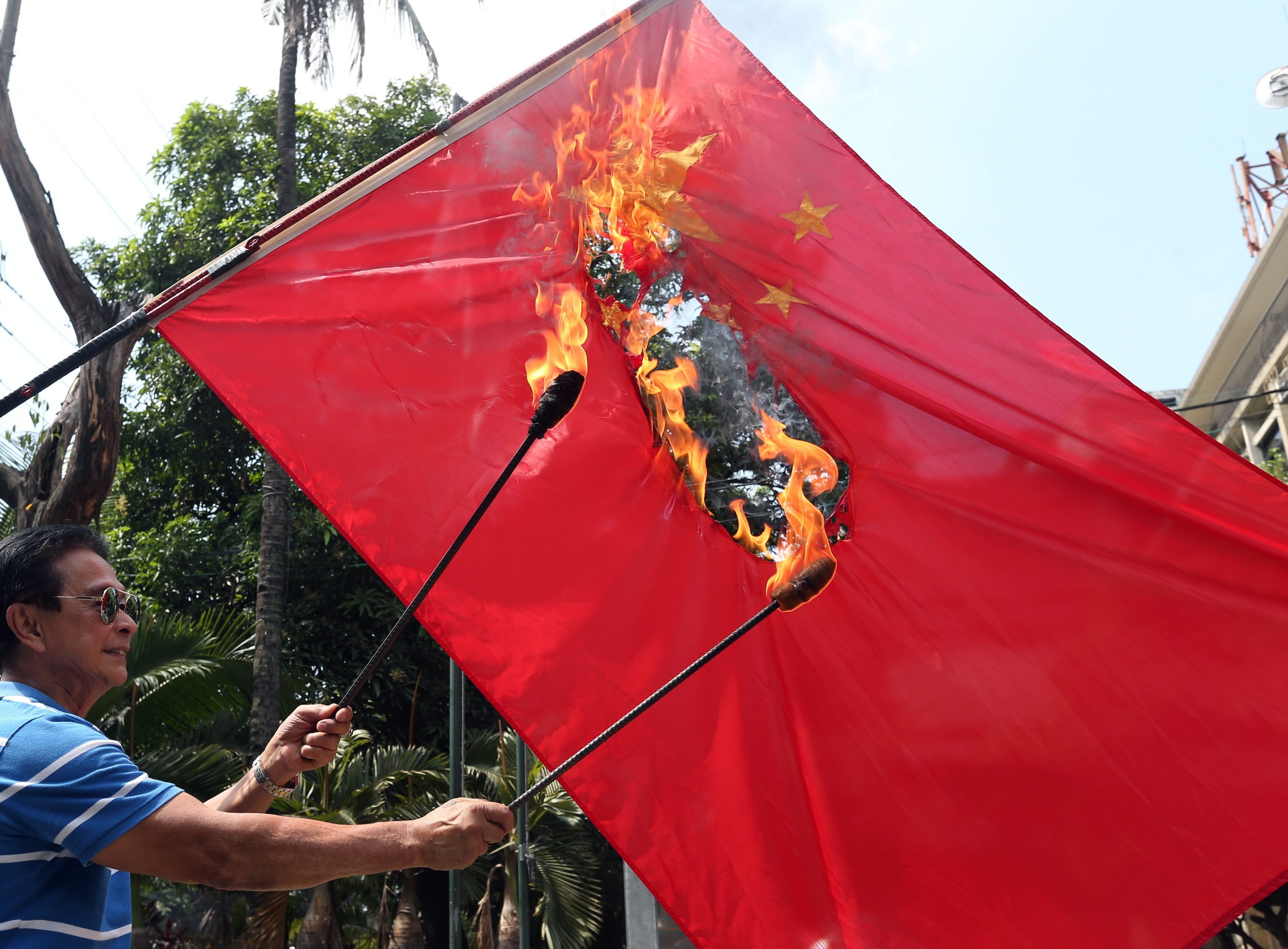 Filipino retired police officer and former town mayor Abner Afuang burns a Chinese flag, in protest over territorial disputes at a shoal in the South China Sea. Photo: EPA