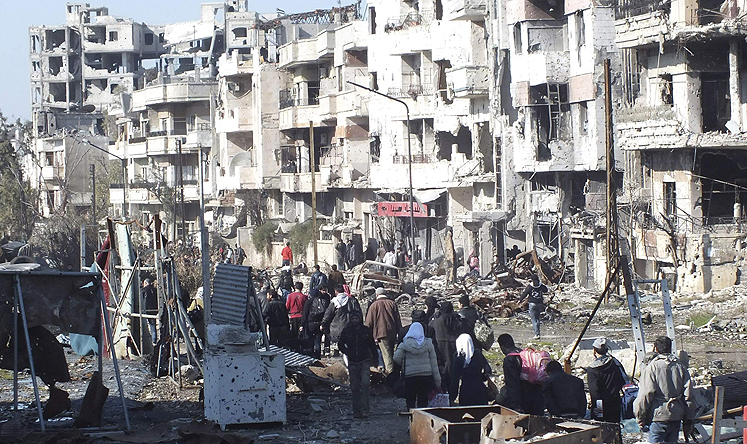 Civilians carry their belongings as they walk towards a meeting point to be evacuated from a besieged area of Homs. Photo: Reuters