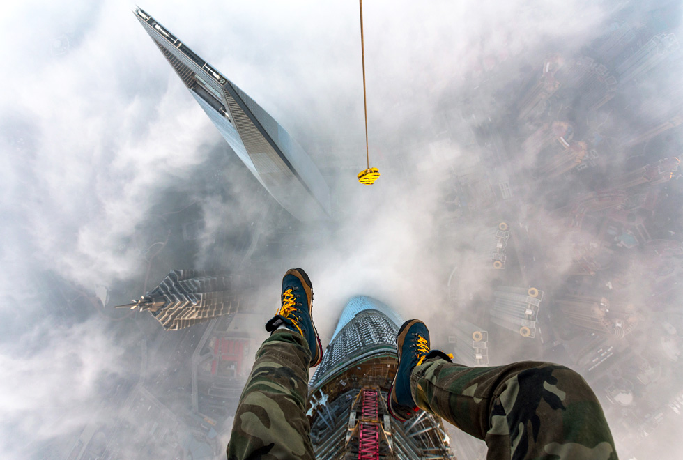 Vitaly Raskalov’s feet dangle above clouds on the top of the Shanghai Tower.