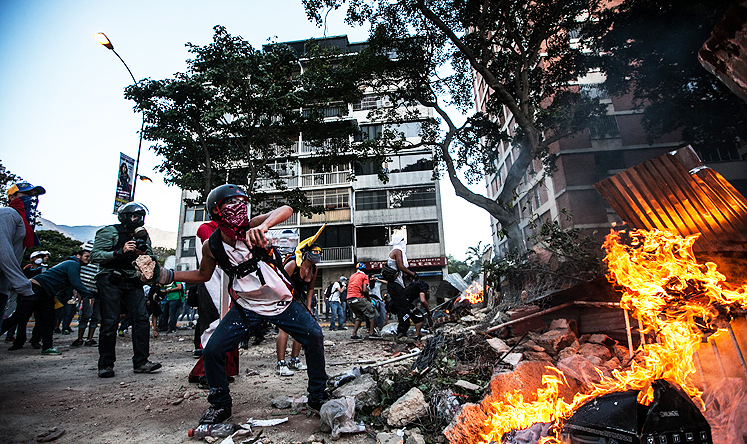 Anti-government demonstrators throw rocks in a clash against the Bolivarian National Police during a protest in Altamira, east Caracas, Venezuela. Photo: Xinhua