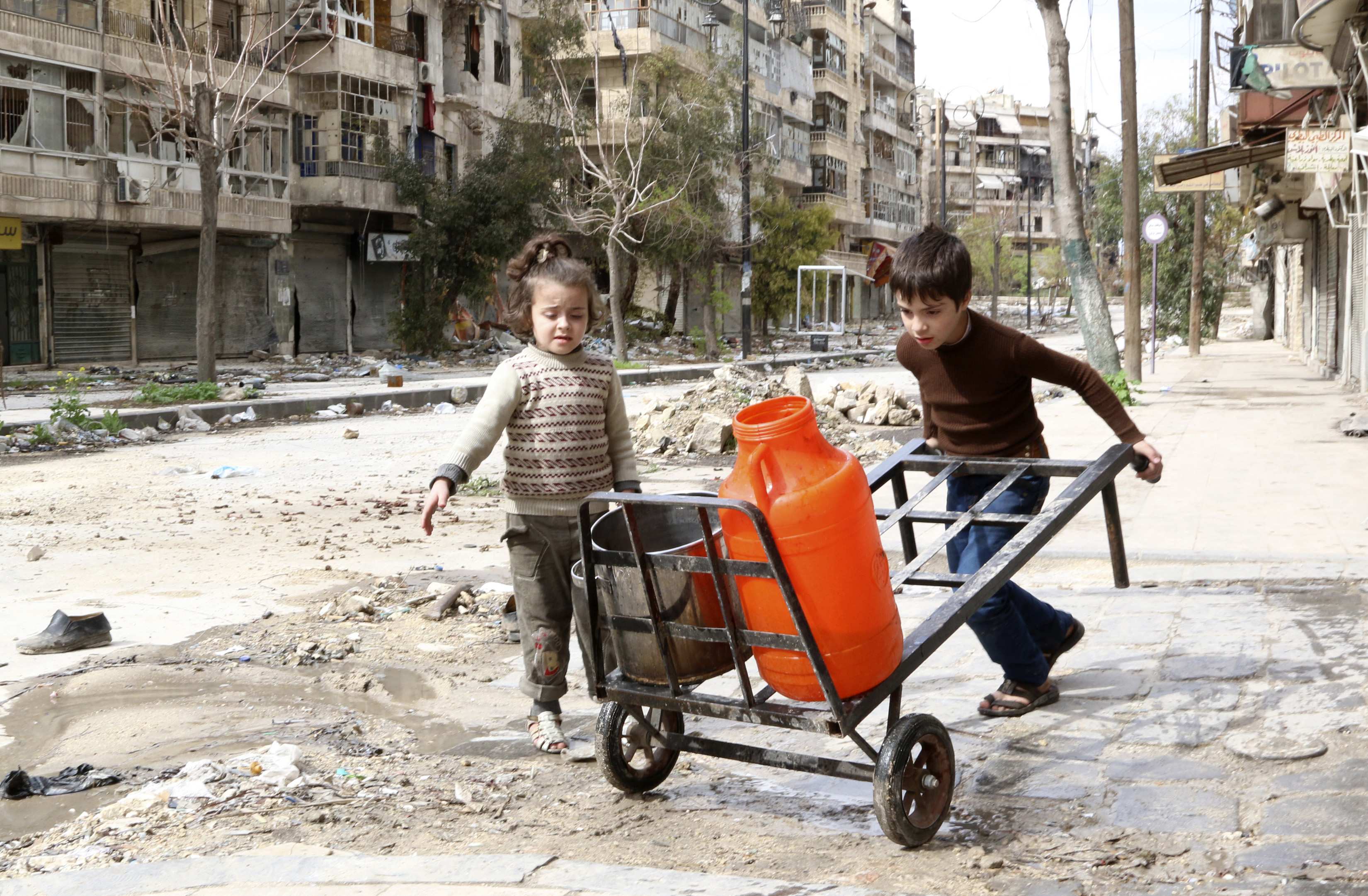 Children push water containers along a street in old Aleppo. Photo: Reuters