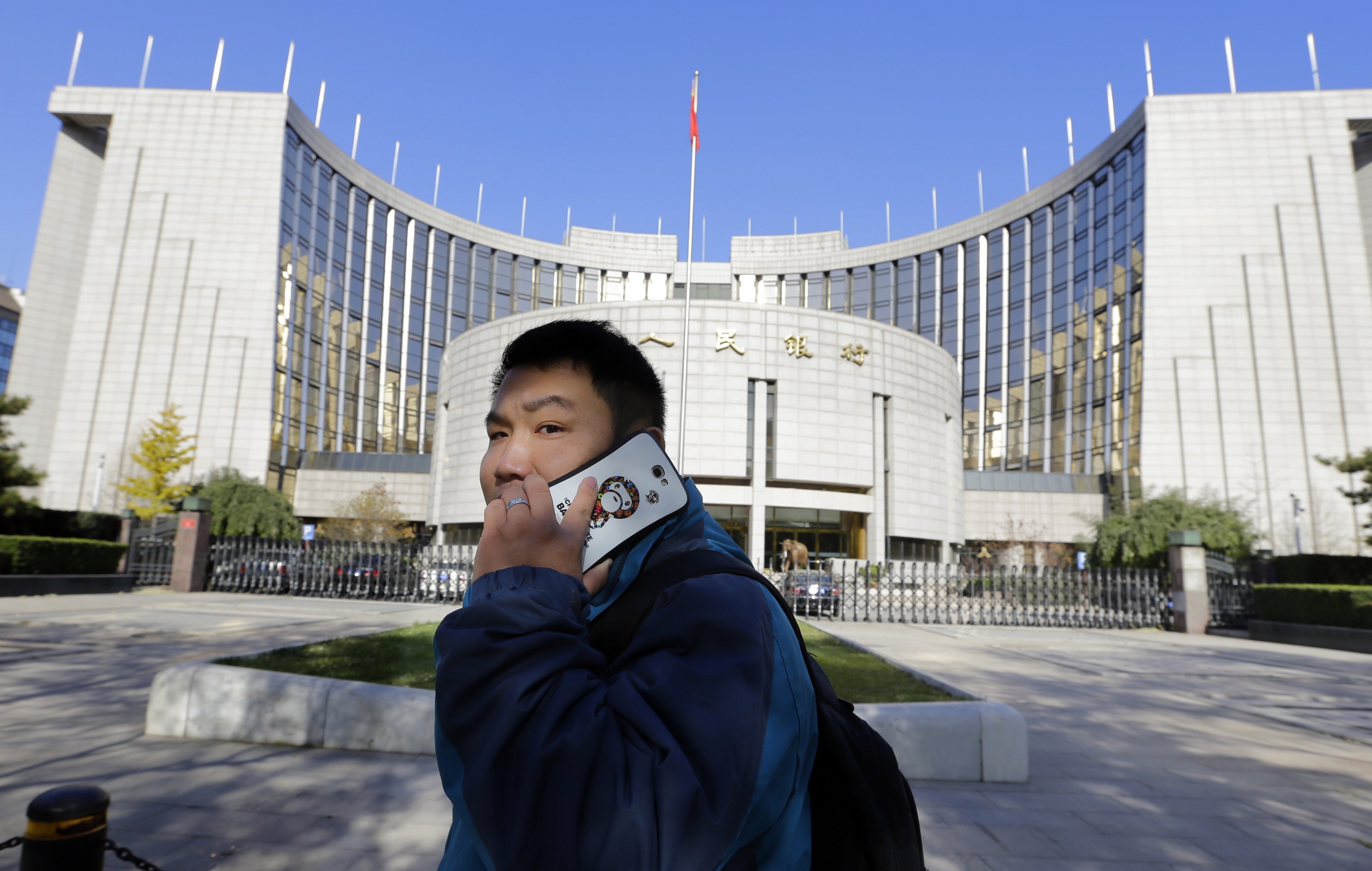 A man uses his mobile phone while walking past the headquarters of the People's Bank of China (PBOC), the central bank, in Beijing. Photo: Reuters