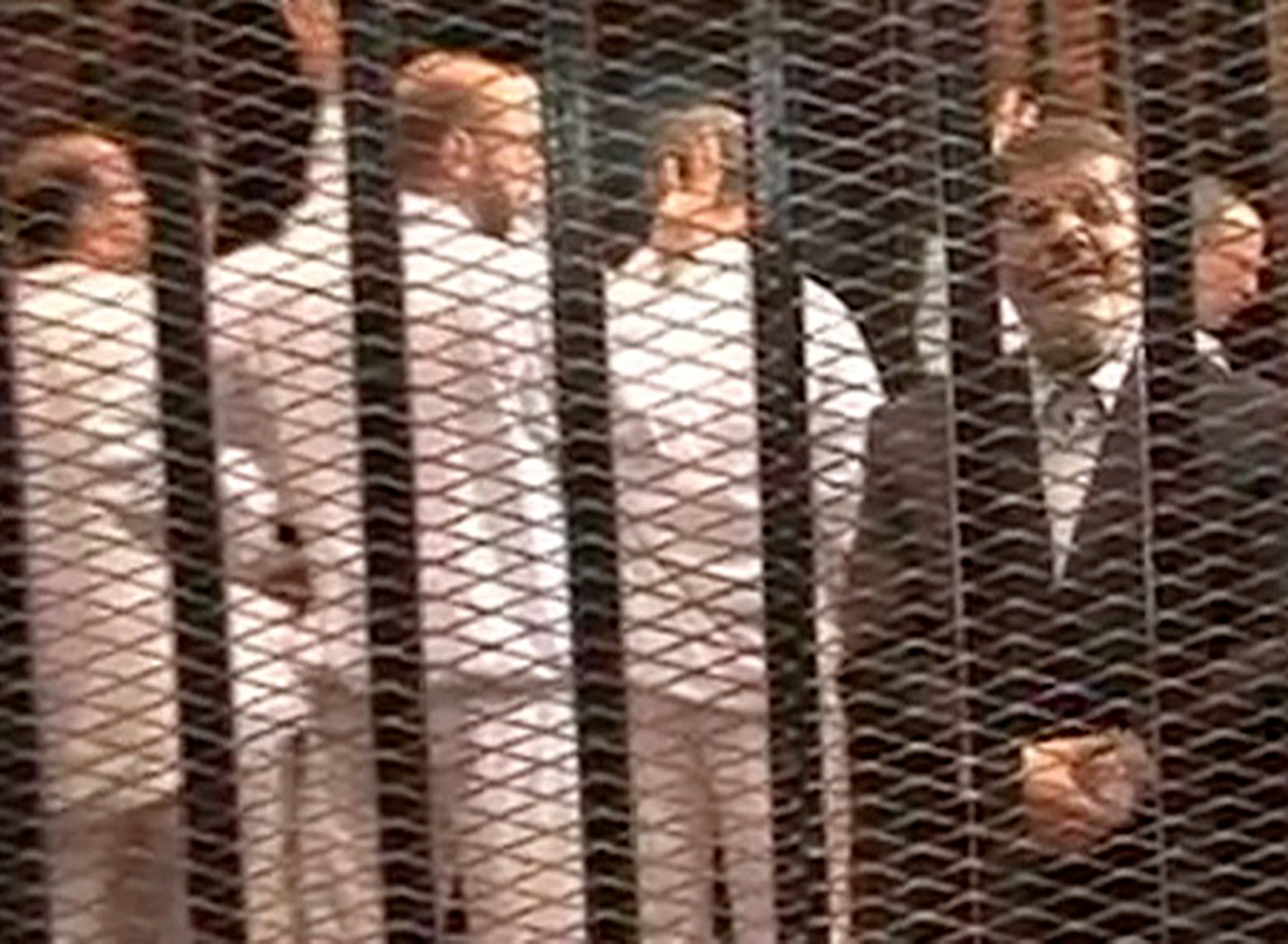 Mohammed Mursi (right) speaks from defendant's cage as he stands with co-defendants during a trial hearing in Cairo. Photo: AP