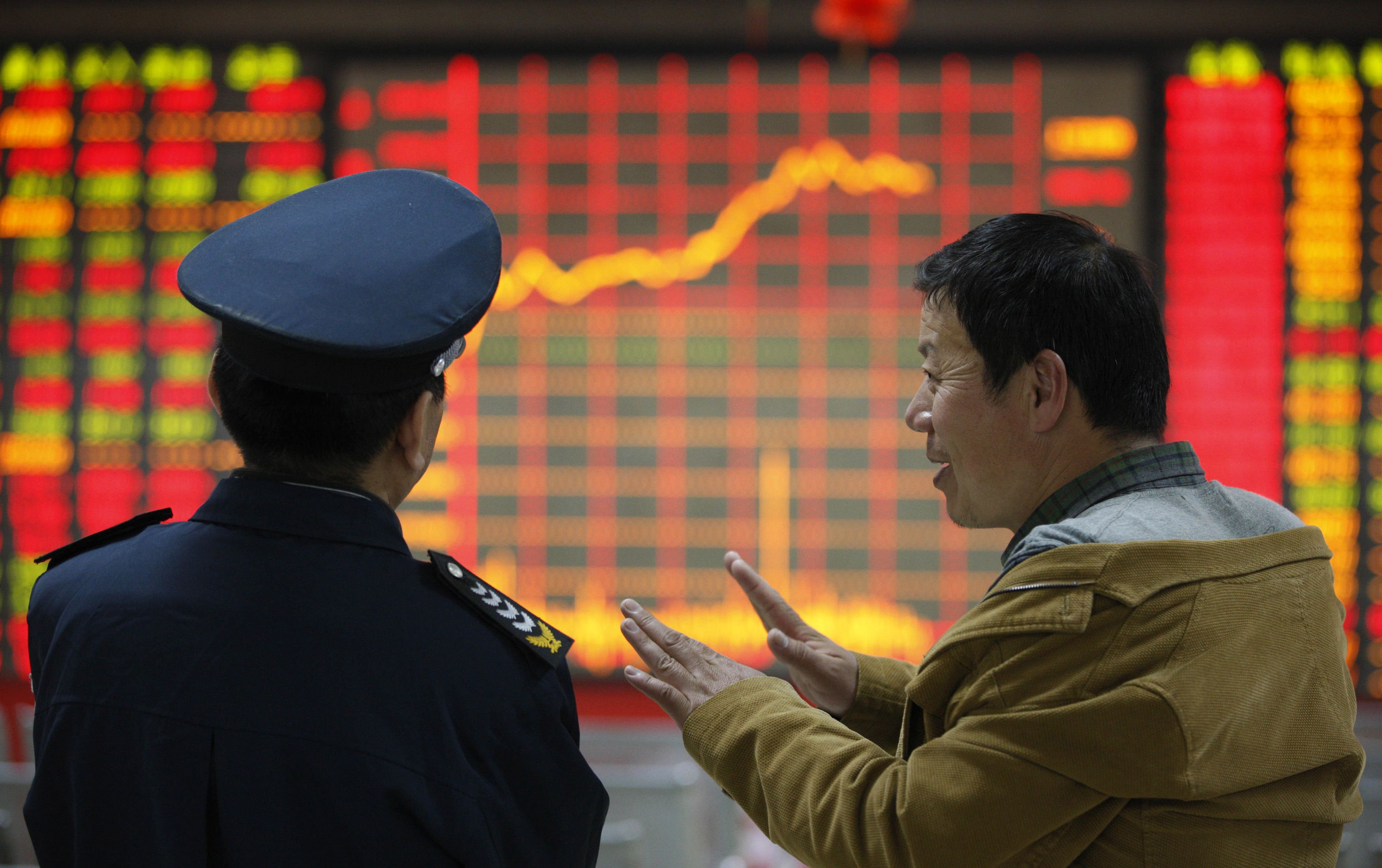 An investor talks to a security guard in front of an electronic board showing stock information at a brokerage house in Huaibei, Anhui province April 8, 2014. 