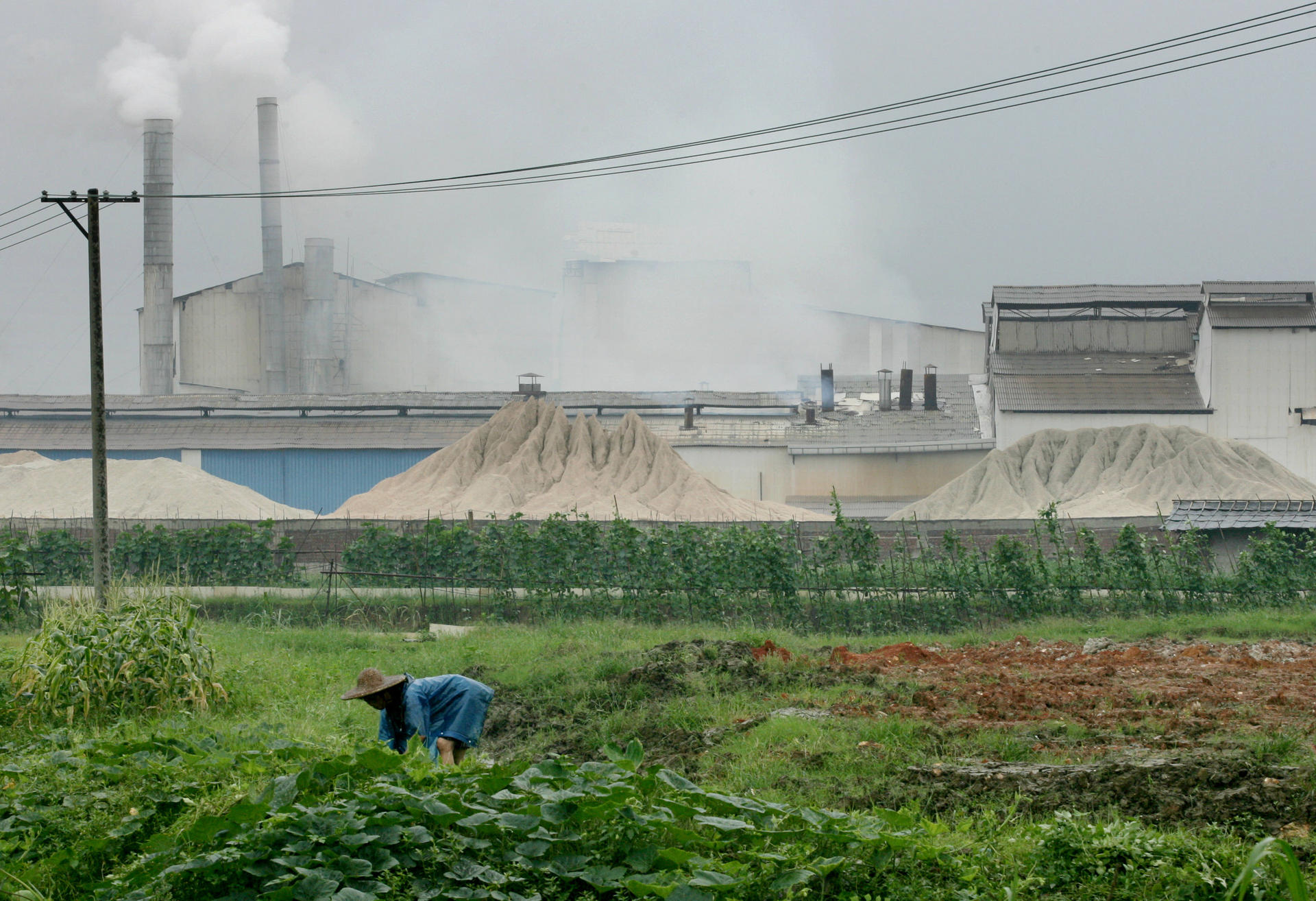 A villager farms in front of a factory in Foshan. Photo: SCMP