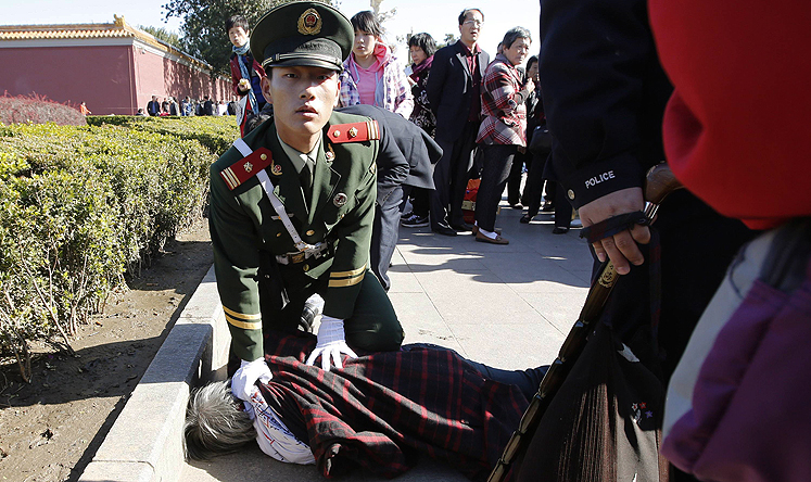 A Chinese paramilitary policeman detains a woman who threw  petition papers near the Forbidden City in Beijing in this file image from October last year. Photo: Reuters