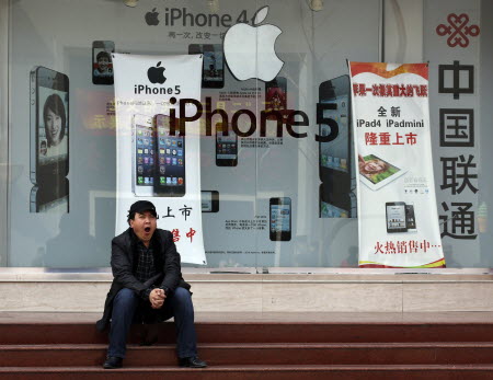 A man yawns in front of a mobile phone shop bearing an advertisement of Apple's iPhone in Beijing. Photo: Reuters