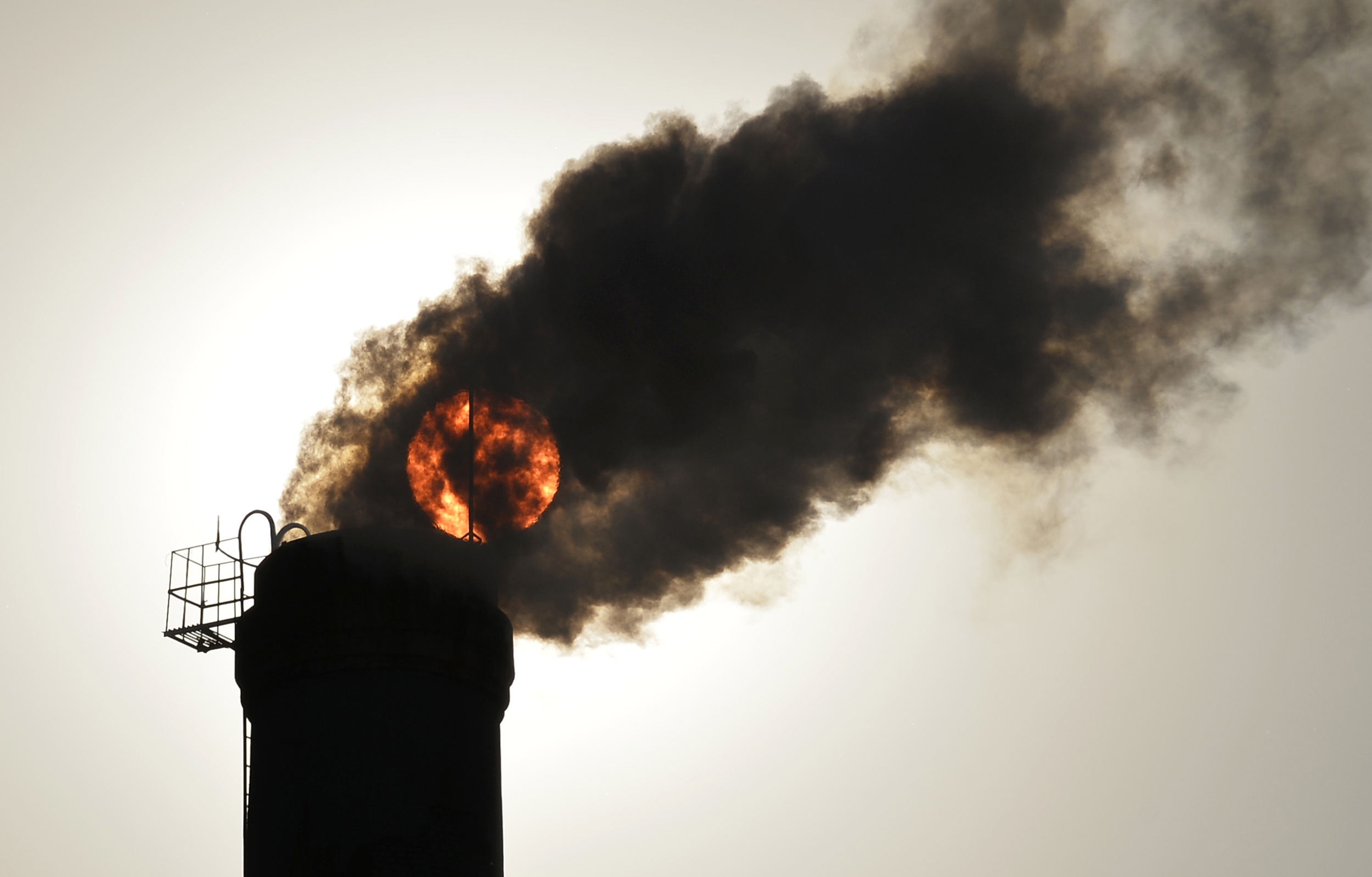 The sun is seen behind smoke billowing from a chimney of a heating plant in Taiyuan, Shanxi province December 9, 2013. Photo: Reuters