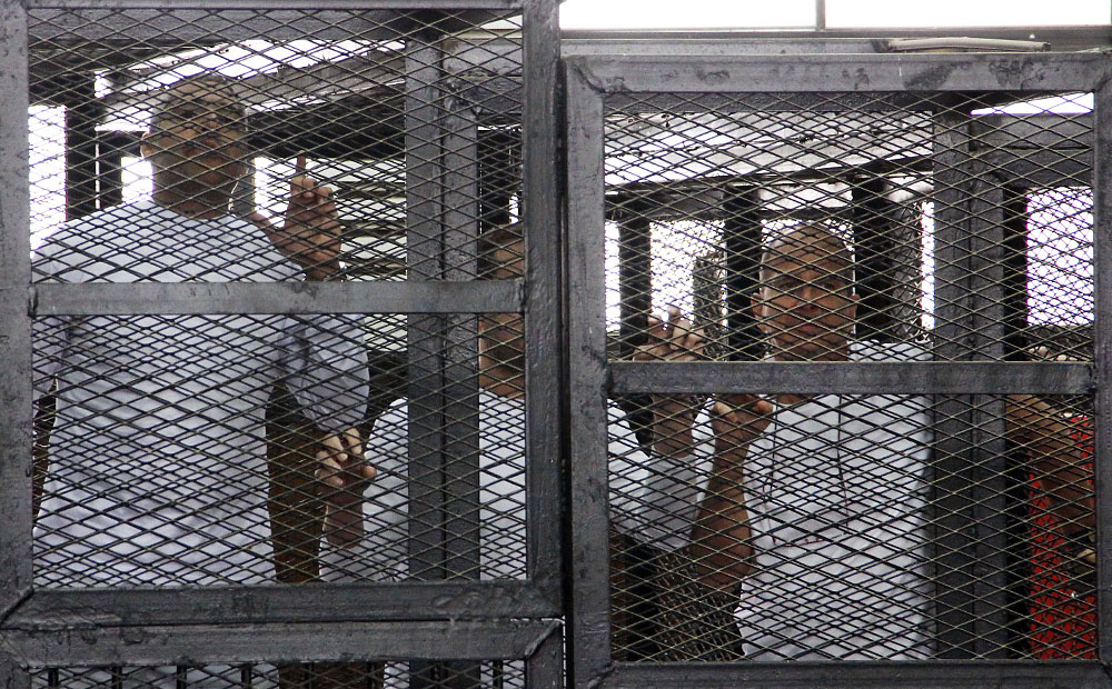 Al-Jazeera English bureau chief Mohammed Fahmy (from left), producer Baher Mohamed and correspondent Peter Greste appear in a defendant's cage in a courtroom along with several other defendants during their trial on terror charges in Cairo. Photo: AP