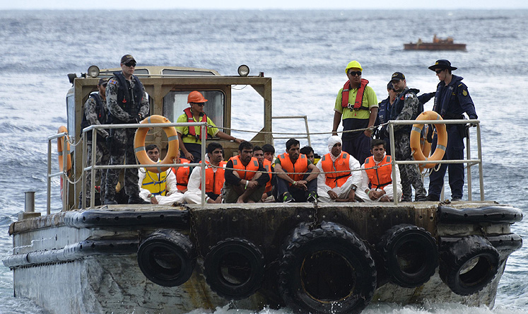 Australian customs officials and navy personnel escort rescued asylum-seekers onto Christmas Island in this image from September 2013. Photo: Reuters