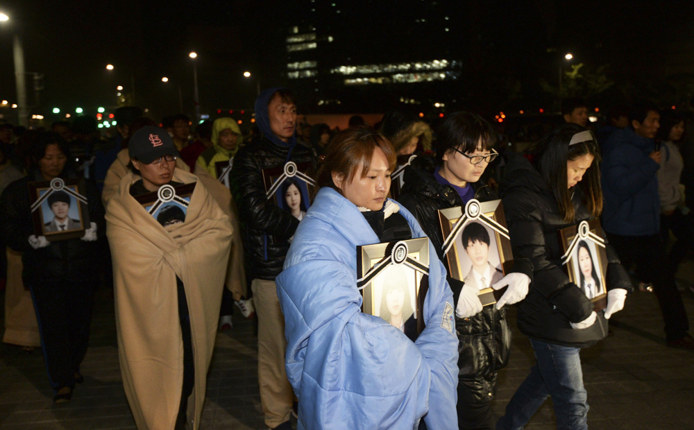 Parents holding portraits of their children who died on sunken passenger ship Sewol march towards the Presidential Blue House in Seoul on Thursday. Photo: Reuters