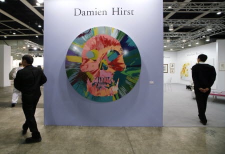 Two men walk past a painting created by artist Damien Hirst at the Art HK 12 art fair. Photo: AP