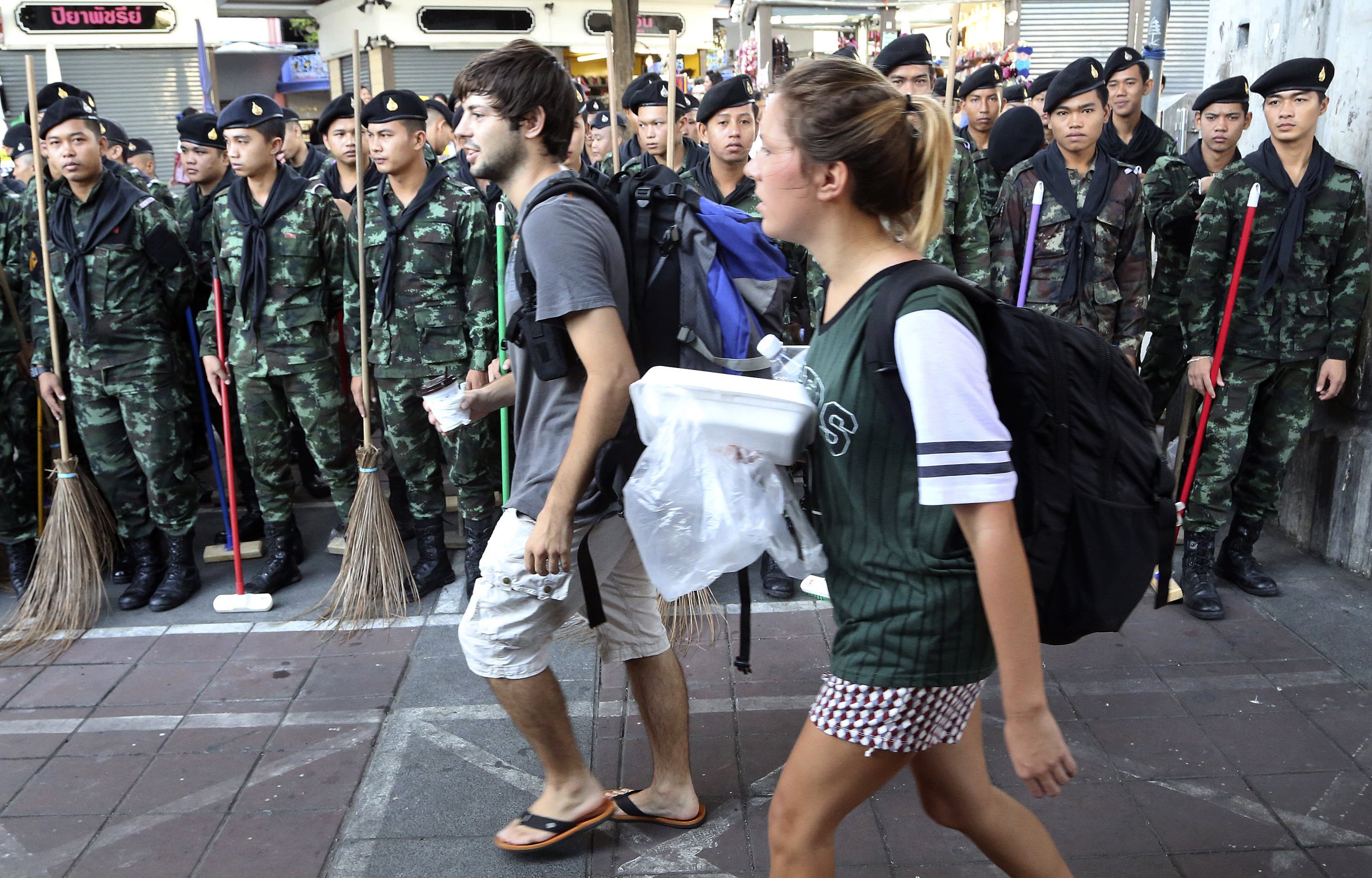 Tourists walk past a line of Thai soldiers armed with brushes and brooms during a joint cleaning operation at Bangkok's Victory Monument. Photo: AP