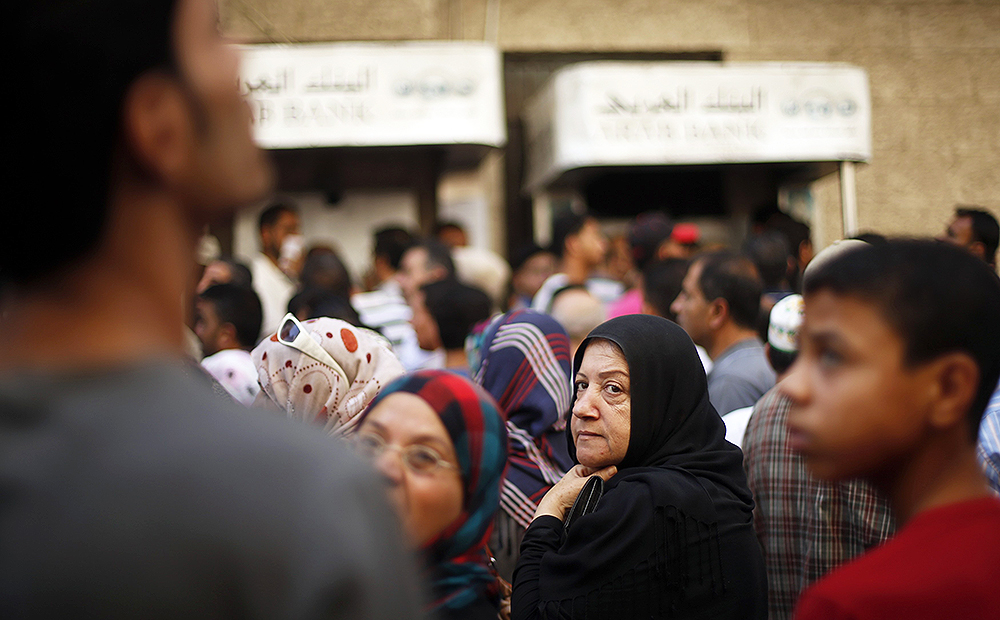 Palestinians wait to withdraw cash from an ATM machine outside a bank in Gaza City. Photo: Reuters