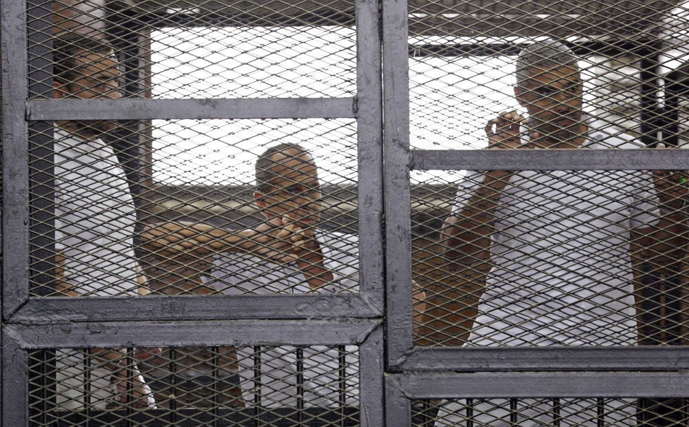 File photo from June 1 of Al-Jazeera journalists Baher Mohammed, Peter Greste and Mohammed Fahmy standing behind bars at a court in Cairo. Photo: Reuters