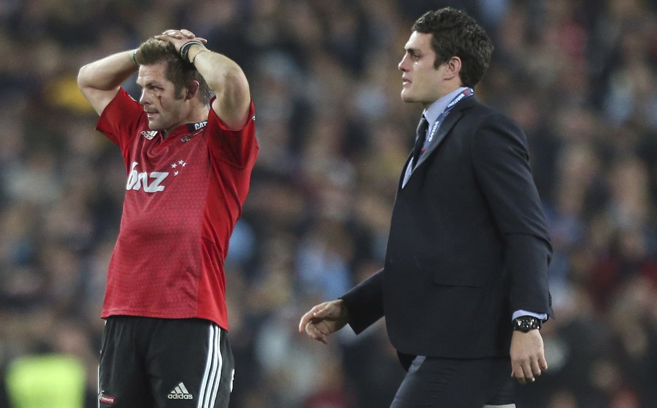 Injured Waratahs’ captain Dave Denis walks past a disappointed Richie McCaw after the Canterbury Crusaders lost the Super Rugby final 33-32 on Saturday. Photo: AP