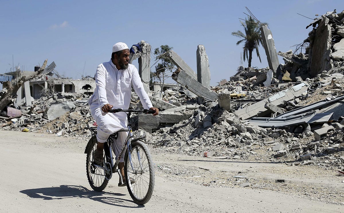 A Palestinian man rides his bicycle past the ruins of destroyed houses in the southern Gaza Strip on Wednesday. Photo: Reuters