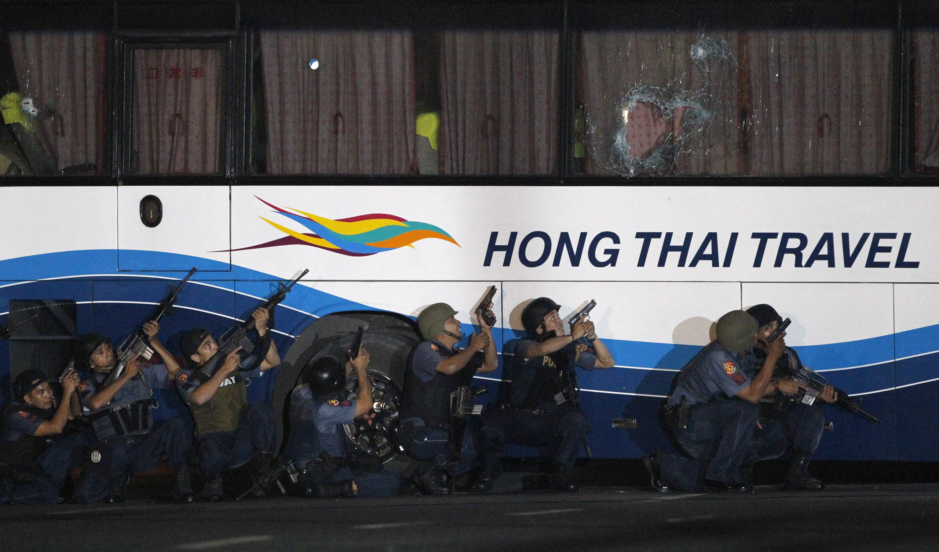 Philippine police commandos crouch with their weapons as they assault a tourist bus that was taken over by a former police officer in Manila. Photo: Reuters