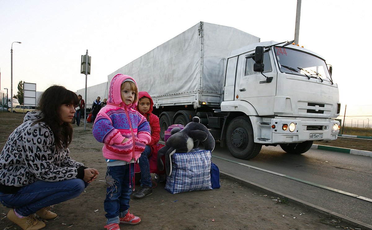Lorries, part of a Russian humanitarian convoy, cross the Ukrainian border at the Donets'k-Izvarino checkpoint early on Saturday as Ukrainian refugees look on. Photo: AFP 