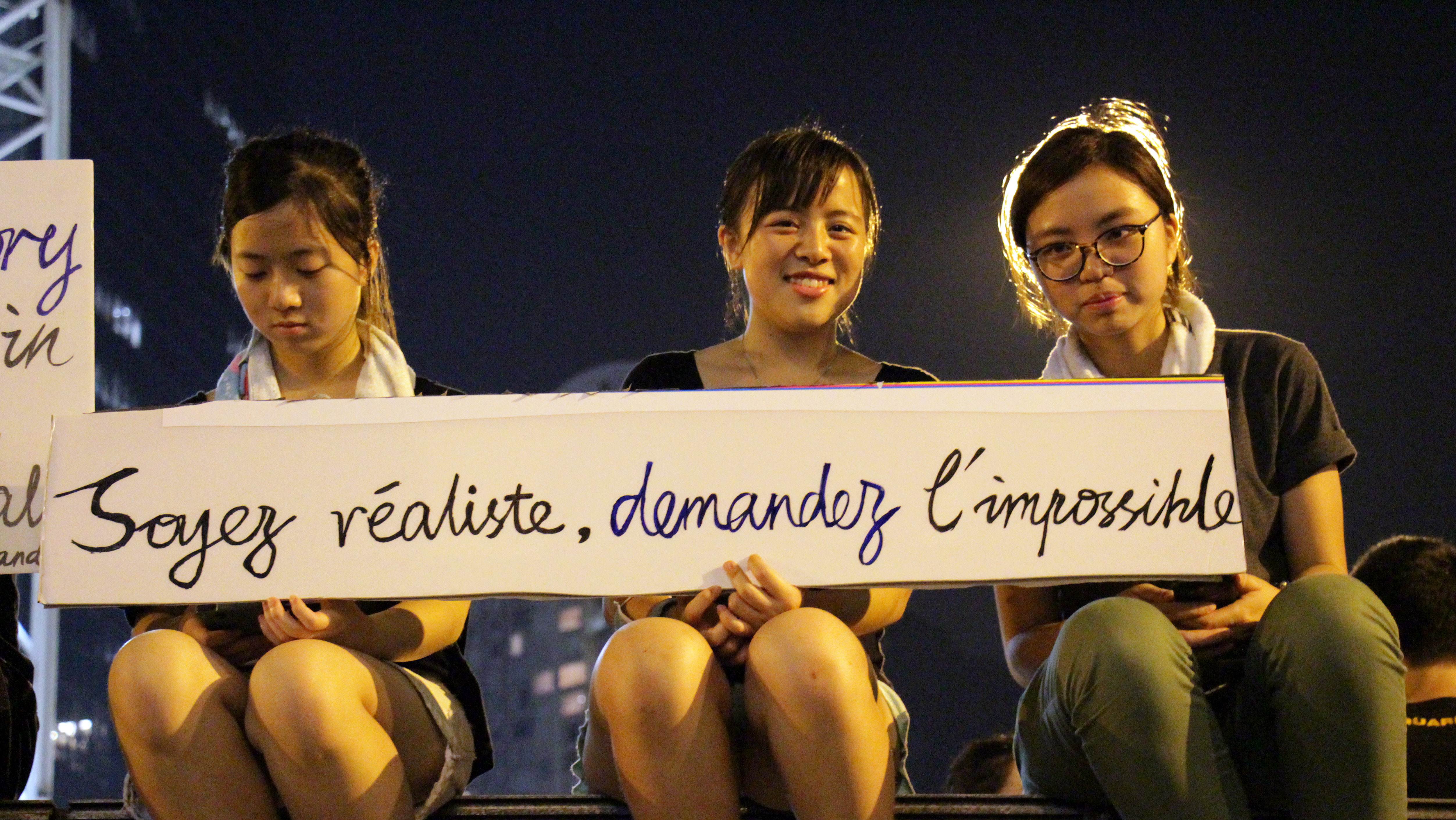 Three students holding a banner that reads "Soyez réaliste, demandez l'impossible" (Be realistic, demand the impossible), a slogan from the Mai 1968 student movement in France, during pro-democracy demonstrations in Hong Kong on Monday. Photo: AFP
