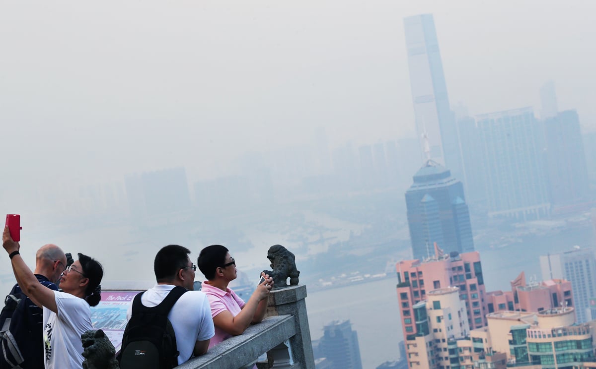 Tourists take photos on The Peak as smog shrouds Hong Kong. The city experienced its smoggiest days of the year in early June and mid-September. Photo: David Wong