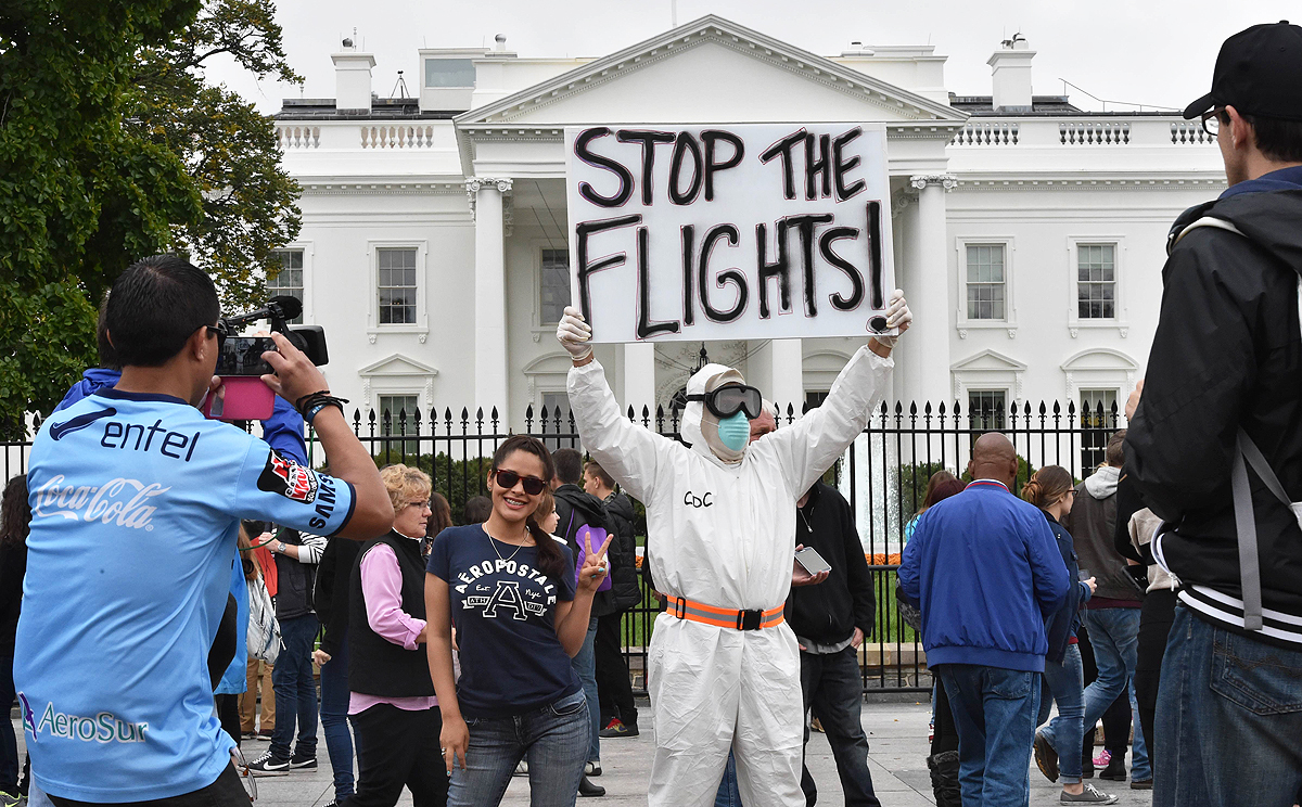 A tourist poses next to Jeff Hulbert from Annapolis, Maryland, dressed in a protective suit and mask demanding for a halt of all flights from West Africa, outside the White House in Washington on Thursday. Photo: AFP