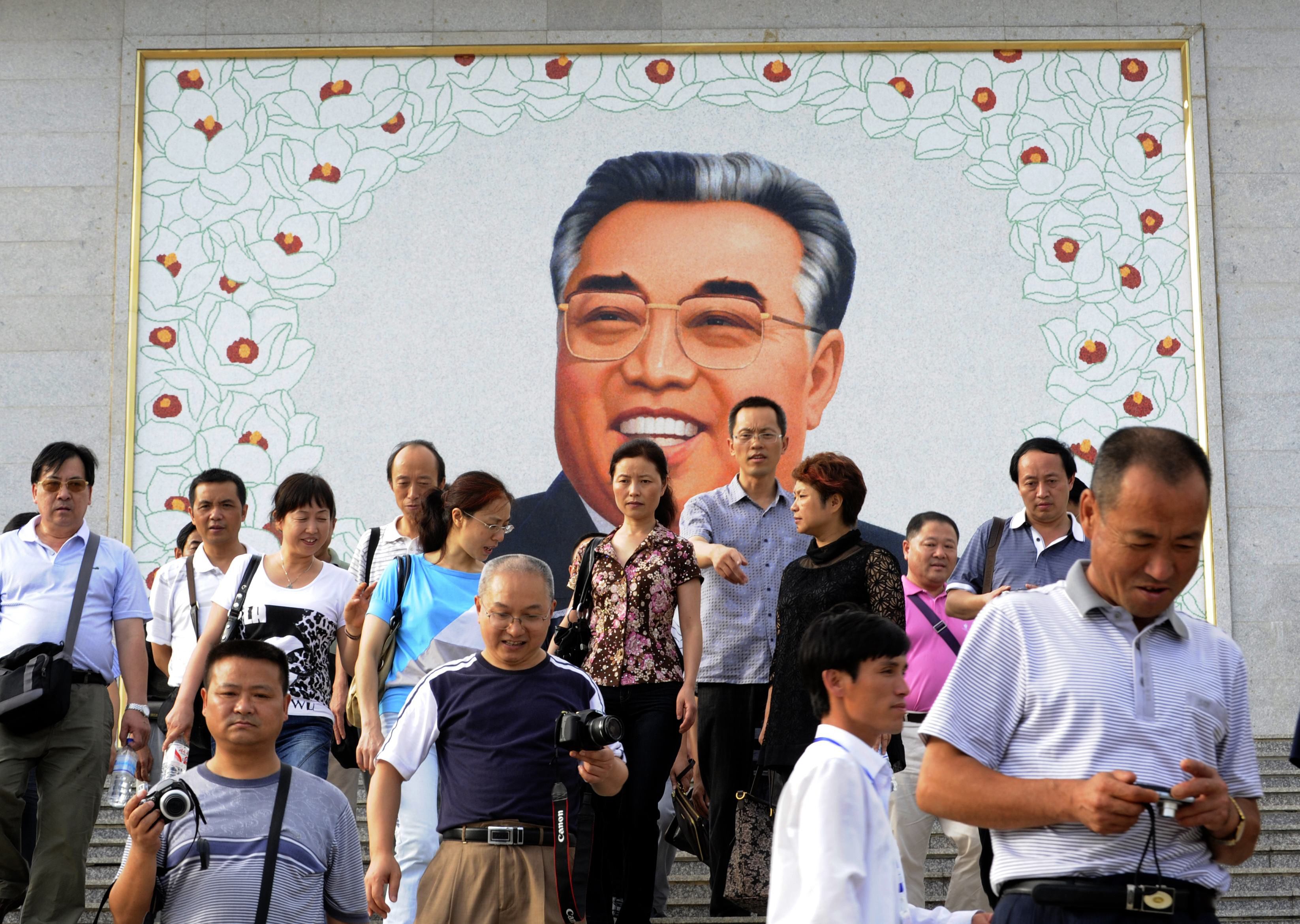 Tourists leaving after paying homage to a giant portrait of Kim Il-Sung. Photo: AFP
