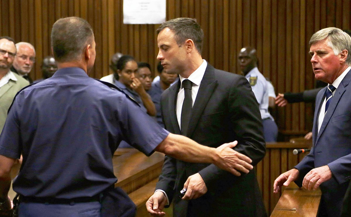 Oscar Pistorius (centre) is led by officer into a holding cell after being sentenced at the high court in Pretoria. Photo: AFP