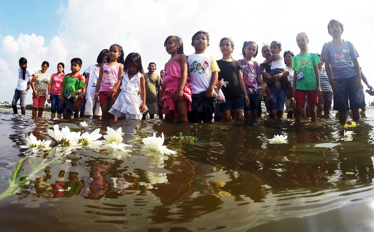 Survivors of Super Typhoon Haiyan in Cavite place flowers into the sea to mark the first anniversary of the disaster, which killed more than 7,300 people when it lashed the Philippines. Photo: Xinhua