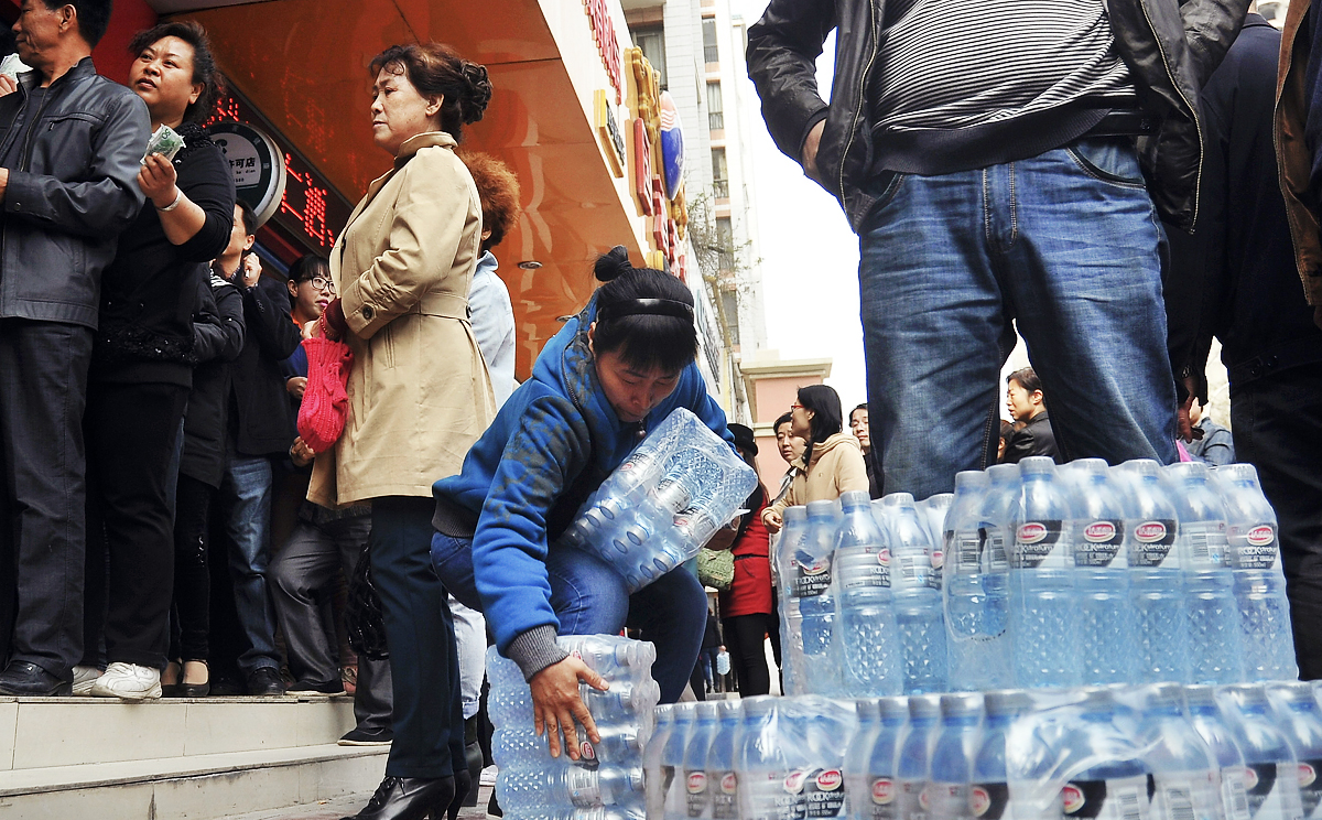 A woman struggles with packs of bottled water she bought in Lanzhou, Gansu province. Many Chinese people rely on bottled water because of high levels of pollution in waterways. Photo: AP