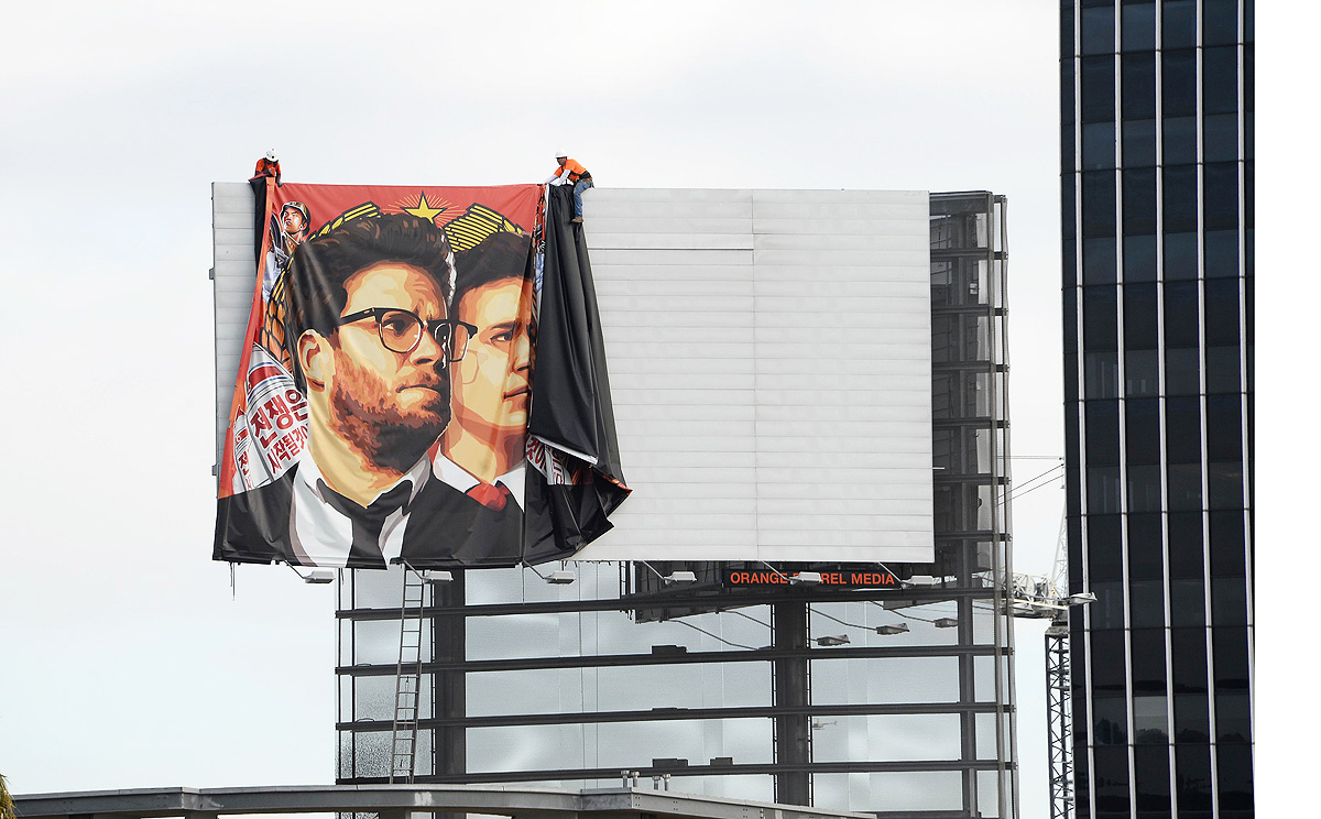 Workers remove a poster for "The Interview" from a billboard in Hollywood, California on Thursday after Sony film studio announced it had no choice but to cancel the movie's Christmas release. Photo: AFP