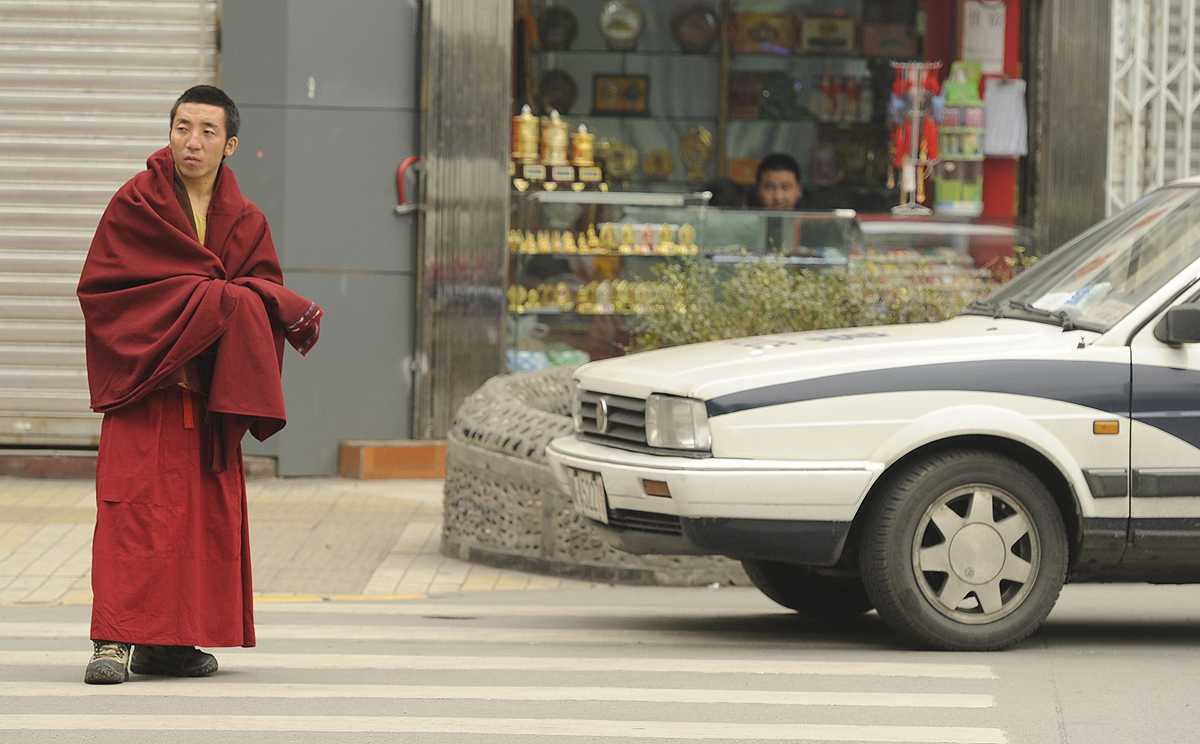 A Tibetan monk walks past a police car on a street in Chengdu, Sichuan province in this file picture from January 2012. Photo: AFP