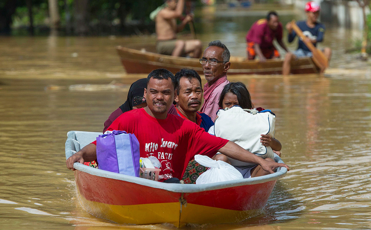 A family ride on a boat through floodwater in Pengkalan Chepa, near Kota Bharu on Friday. Photo: AFP