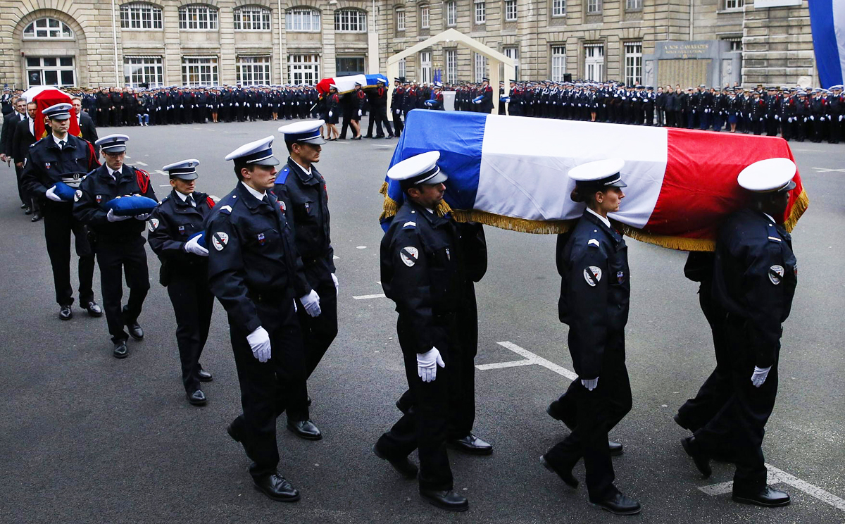 Police officers carry the coffins draped in the French flag of their three colleagues killed in last week's Paris attacks as they were posthumously decorated with the Legion d'honneur at the Invalides Hotel in the French capital yesterday. Photo: Reuters
