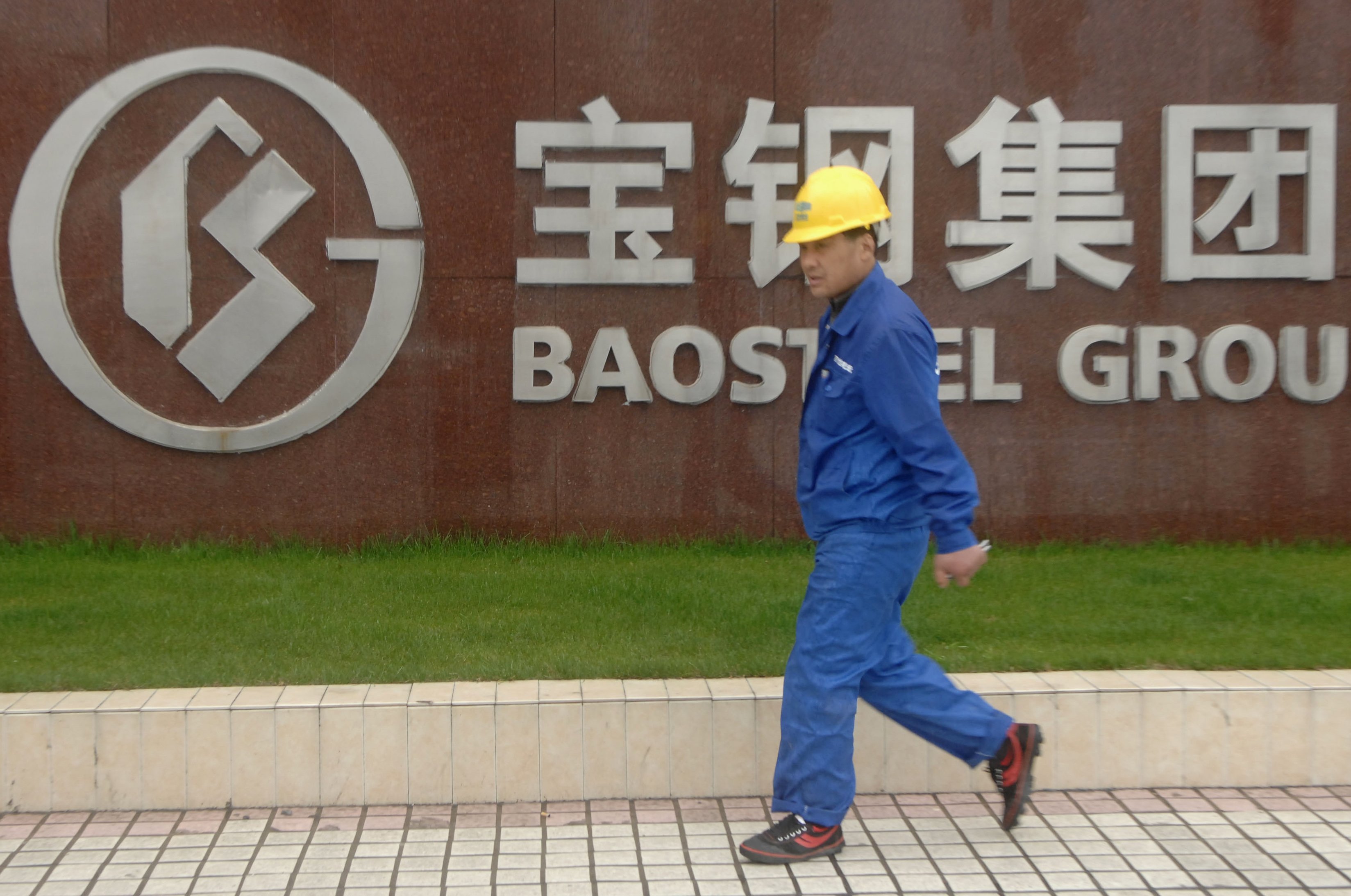A worker strides past logo of Baoshan Iron & Steel. The most profitable steel company in China said its net profit was flat. Photo: Reuters