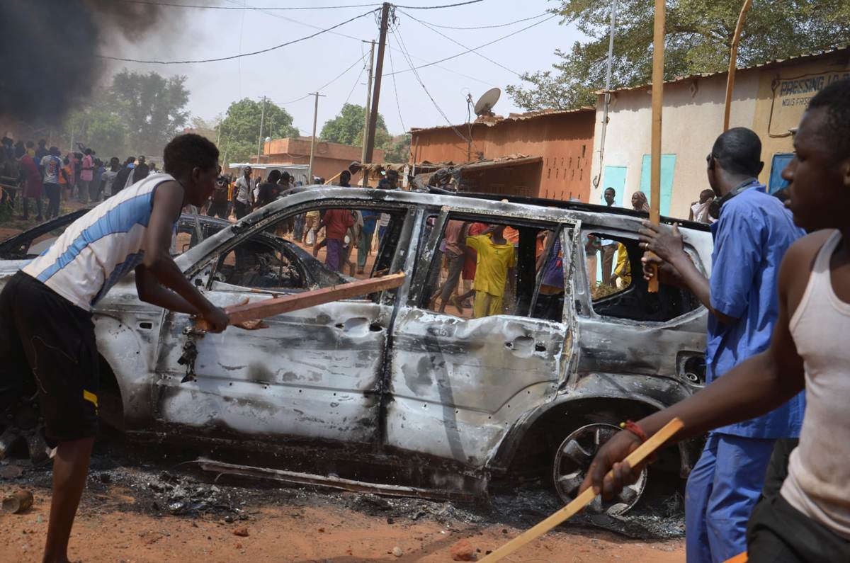 People carry sticks near damaged cars during a demonstration against Charlie Hebdo’s Mohammed cartoon in Niamey. Photo: AFP