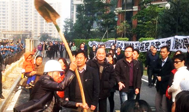 A building worker threatens residents with a shovel during yesterday's clashes. Photo: China National Radio