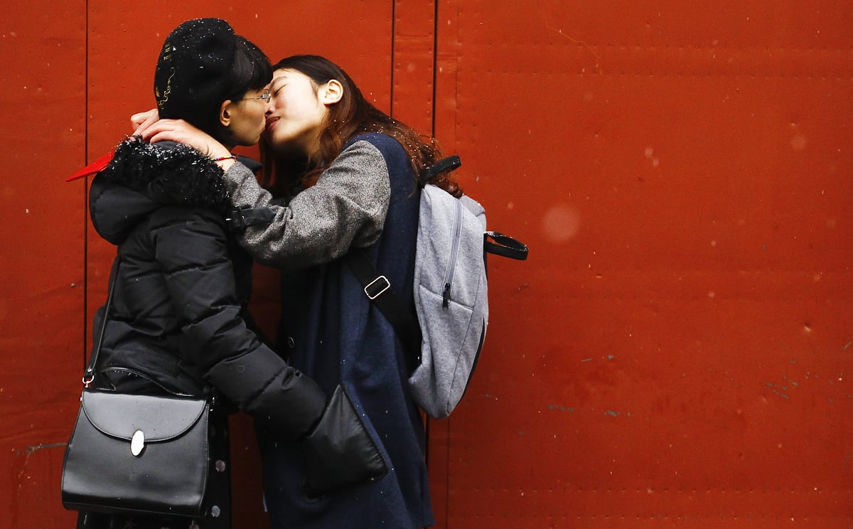 A lesbian Chinese couple kiss for the cameras outside a marriage registry office after being turned away. Some lesbians are opting to marry gay 'beards' to ease social pressure and discrimination. Photo: EPA